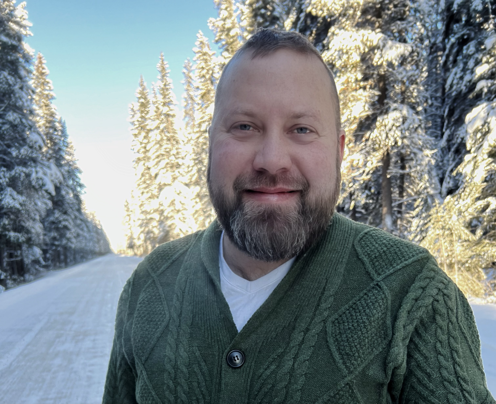 Photo of Doug Winkelaar with snowy trees behind